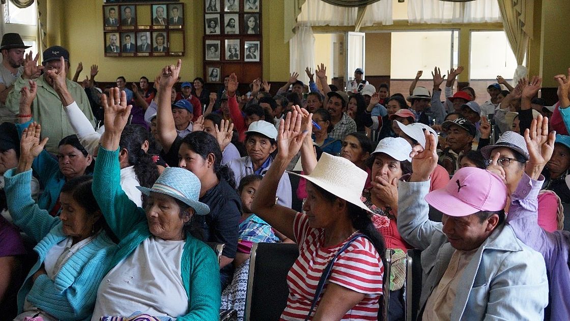This photo shows Ecuadorians sitting in a room, some of them have their hands raised high - a vote is being carried out.