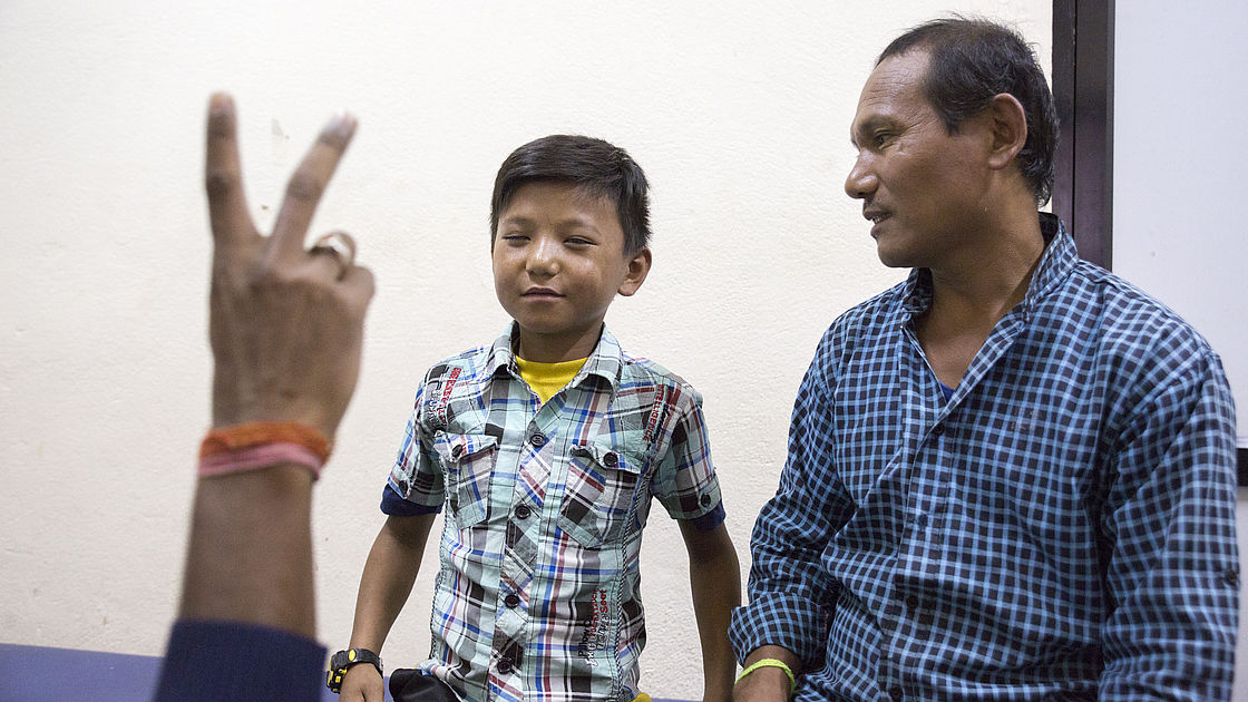 This photo shows a young boy's vision being checked, while his father looks on.