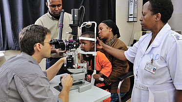 CBM's Dr. Heiko Philippin and his team examine the eyes of Joyce (who had a successful bilateral cataract operation) at the KCMC Hospital, Tanzania