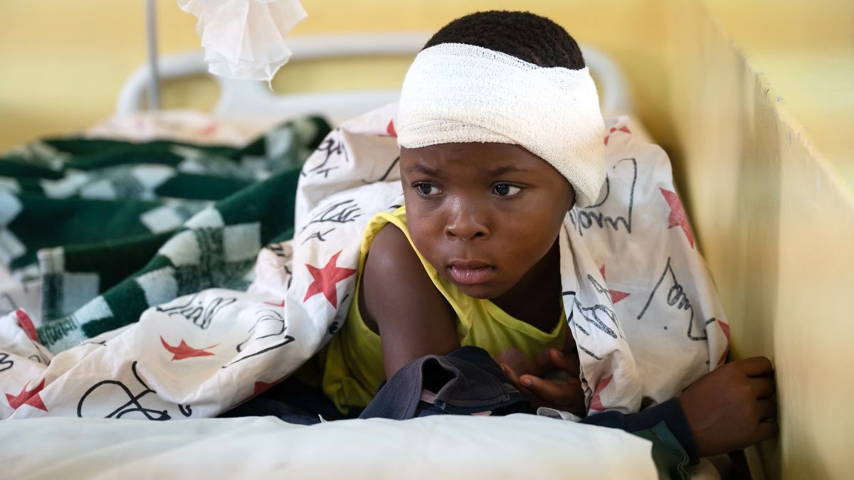 Mädchen mit Kopfverband auf einem Krankenhausbett.