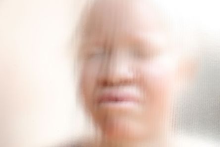 Gesicht einer hellhäutigen afrikanischen Frau hinter einer Strukturglasscheibe