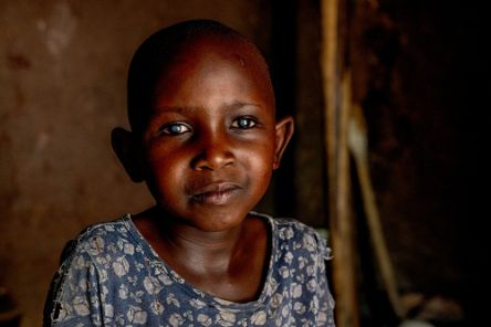 Ein kleines Mädchen mit auffallend hellen Pupillen in einem dunklen Raum.