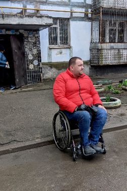 A man in a wheelchair outside a destroyed building