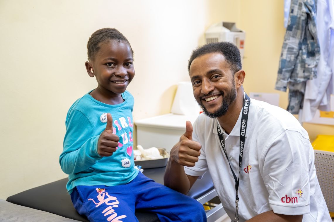 Ein Mann und ein etwa zehnjährigen Mädchen halten den Daumen hoch und lachen.