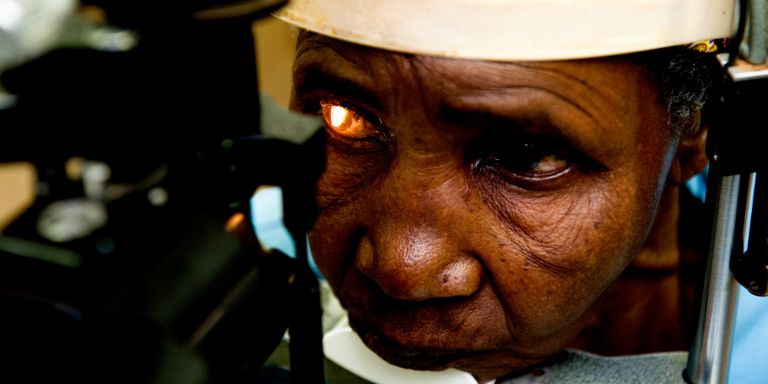 An elderly African woman gets an eye exam.