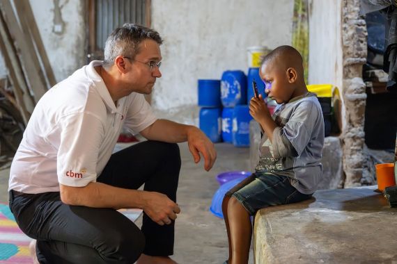 Ein Mann sitzt in der Hocke vor einem etwa vierjährigen Kind.
