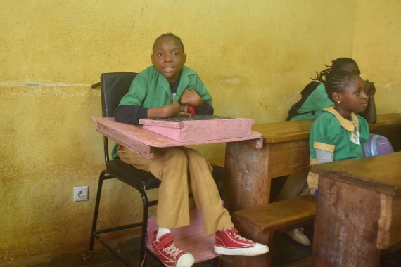 Ein Mädchen sitzt in einem Hochsitz gemeinsam mit anderen Kindern in einem Klassenraum.