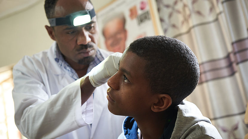 A male doctor is examining a teenage boy's ear