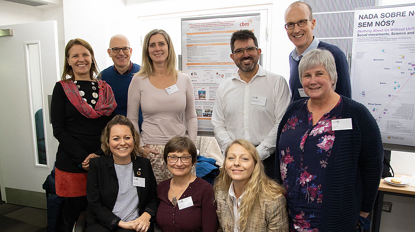 9 CBM colleagues gather for a photo in front of a CBM poster-presentation