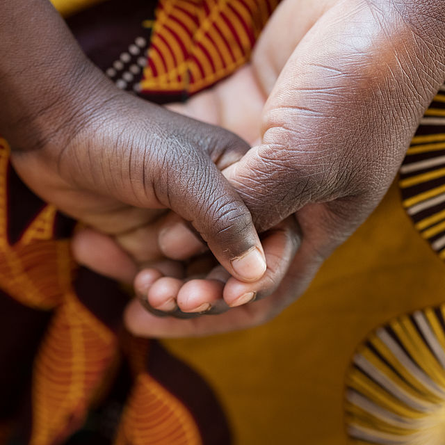 close up at 2-year-old holding hands with his mother