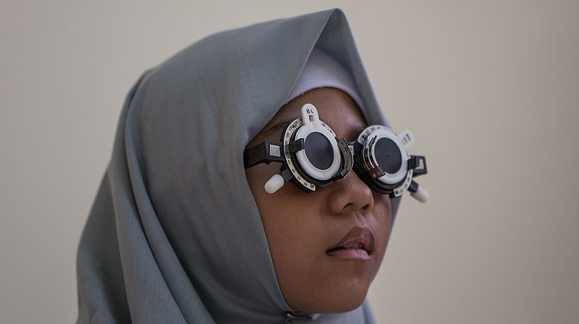 A girl from Indonesia wears special glasses to calculate an eyeglasses prescription.