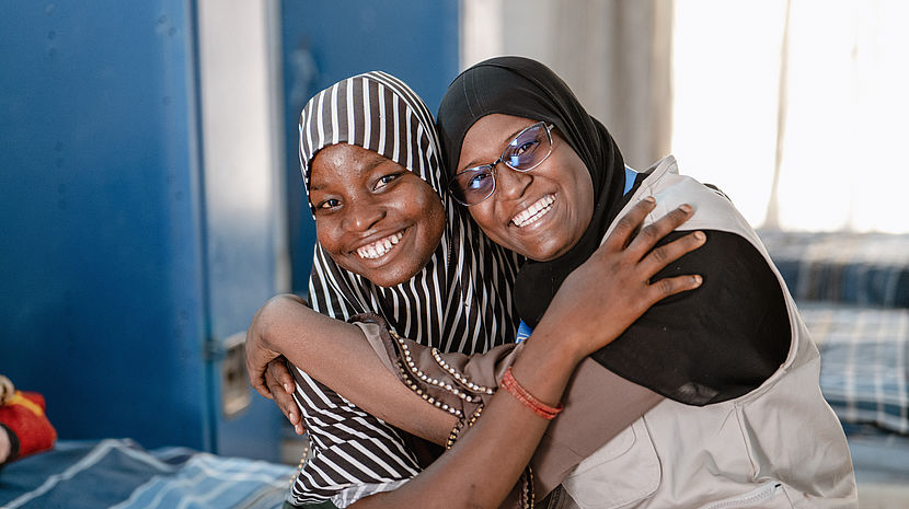 Two African women are hugging and smiling