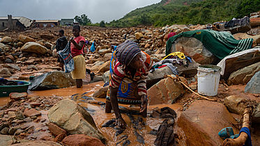 An elderly woman washes her belongings in the mud on March 19, 2019, in Chimanimani, Zimbabwe, after the area was hit by the Cyclone Idai © ZINYANGE AUNTONY / AFP