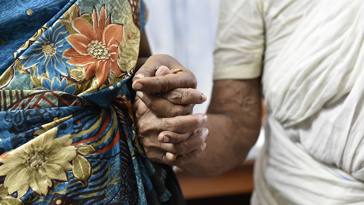 Mother and daughter hold hands the day after 75-year-old Thanka had cataract surgery at a CBM-supported hospital.