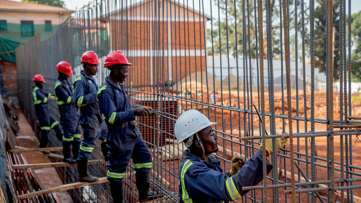 Men wearing helmets at a construction site are building a eye health complex in Uganda 