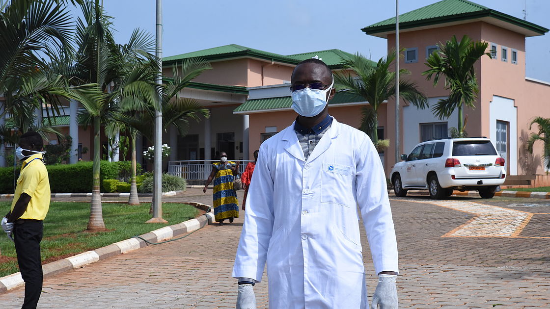 This photo shows a doctor wearing a white coat and a mask on his face.