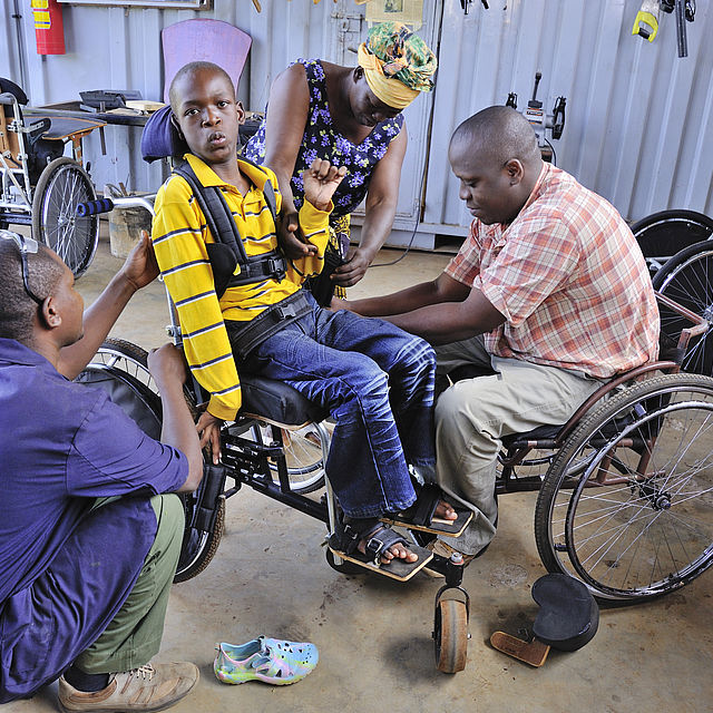 Wheelchair technologist Abdullah adjusts Japhet's wheelchair